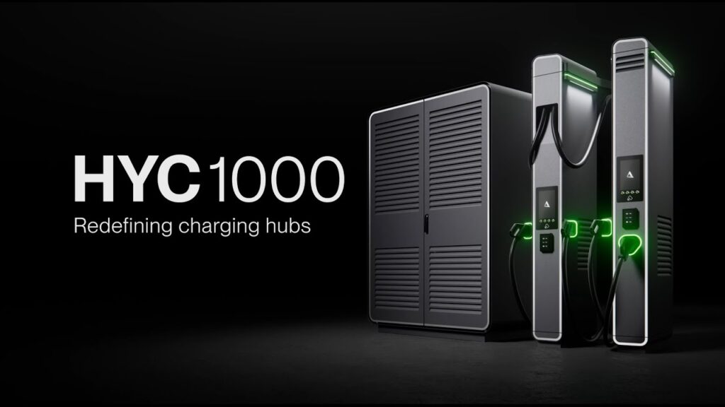 Alpitronic HYC1000 DC-snabbladdningssystem med kraftskåp och två moderna laddningsdispensers, belysta med gröna LED-lampor. Texten 'HYC1000 – Redefining charging hubs' visas på en mörk bakgrund.